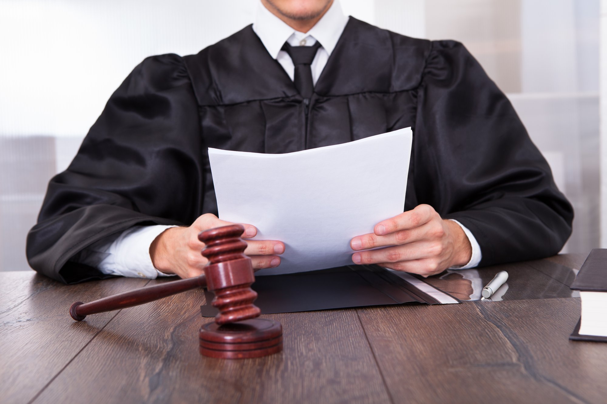 Judge in a robe reading a document at the bench