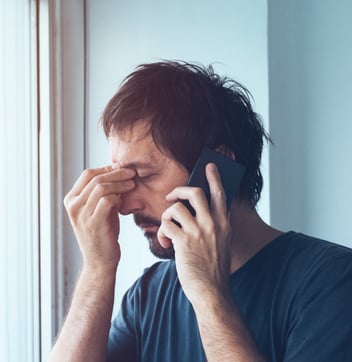 Stressed man talks on the phone.