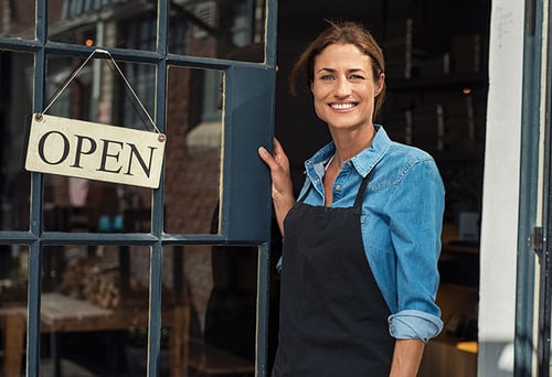 A woman business owner standing in front of her shop.